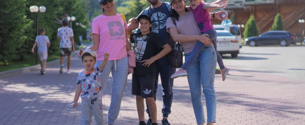 A joyful family of six spending quality time together in a scenic outdoor setting with mountains in the background.